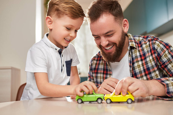 Cheerful father and son playing with cars - Фото, изображение
