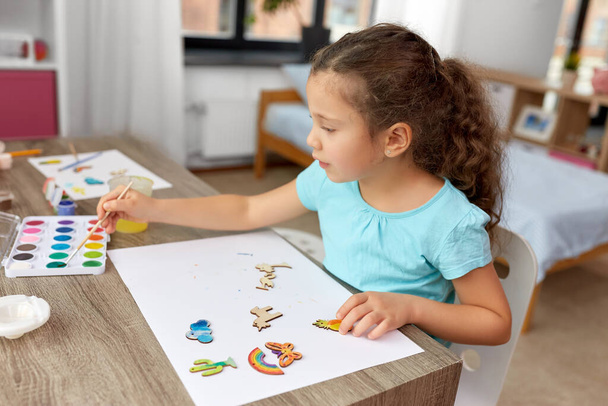 little girl painting wooden items at home - Foto, Imagem