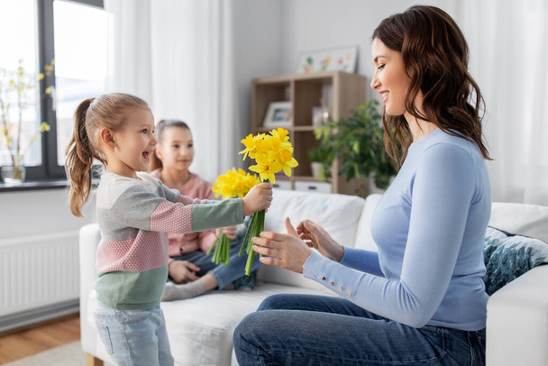 daughters giving daffodil flowers to happy mother - Foto, Imagen