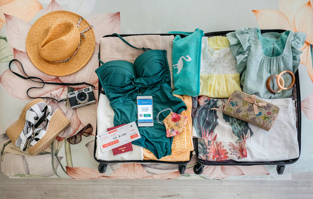 Plaj tatili ve dijital sağlık pasaportu için kadın valizini aç. - Fotoğraf, Görsel