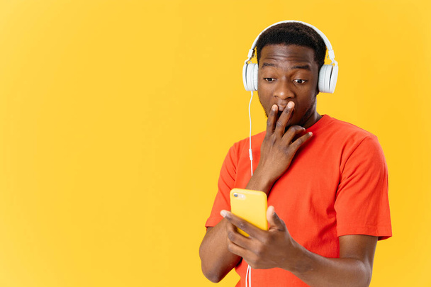мужчина в наушниках с телефоном в руках слушает музыку удивленным взглядом - Фото, изображение