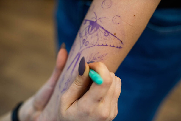 Cerca del tatuaje temporal en el brazo del cliente que hace trabajador. Preparación. Transfiera el boceto al cuerpo. - Foto, Imagen