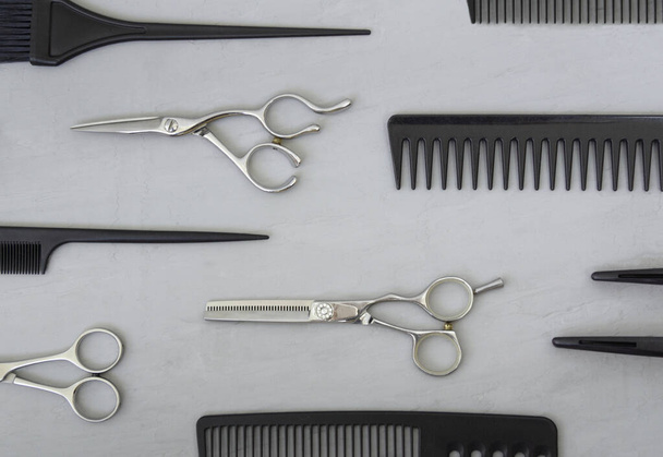 Marco completo con herramientas de peluquería, peines, tijeras sobre un fondo gris. Accesorios de peluquería, vista superior. - Foto, imagen