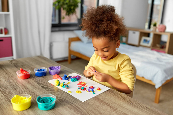 little girl with modeling clay playing at home - Foto, imagen