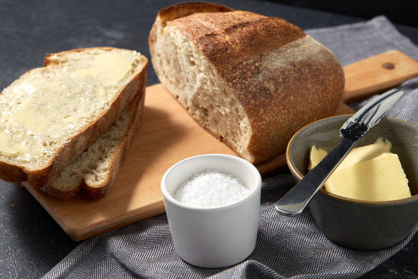 close up of bread, butter, knife and salt on towel - 写真・画像