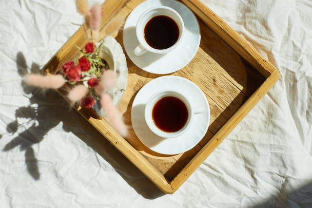 Ontbijt op bed, proberen met twee kopjes koffie en bloem in het zonlicht thuis, kamermeisje brengen dienblad met ontbijt op de kamer van het hotel, goede service - Foto, afbeelding