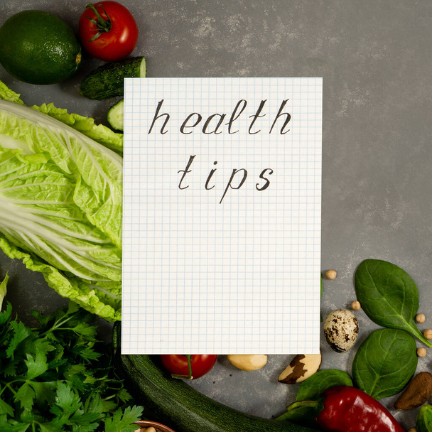 Diet plan with greens and fresh vegetables in a paper notebook on a gray table surface. - Photo, Image