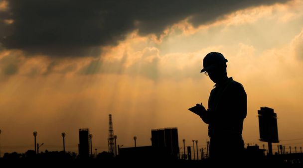 Engineer use digital tablet at construction site, in sunset silhouette - Photo, Image