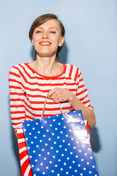 Beautiful woman holding shopping bags over blue background - Photo, Image