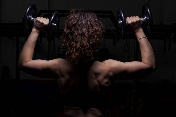 A woman from behind lifting weights in the gym - Fotoğraf, Görsel
