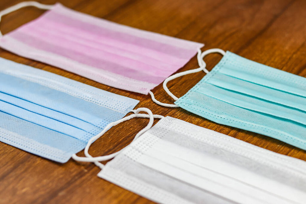 A selective focus shot of colorful surgical cotton masks on a wooden surface - Foto, afbeelding