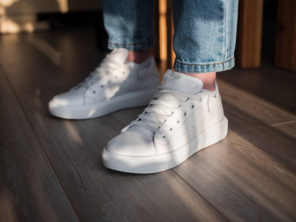 A closeup shot of a woman showing her white shoes in the room - Foto, afbeelding