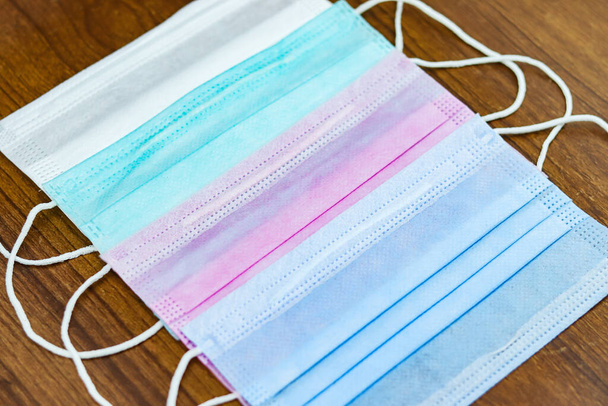 A shot of colorful surgical cotton masks on a wooden surface - Photo, Image