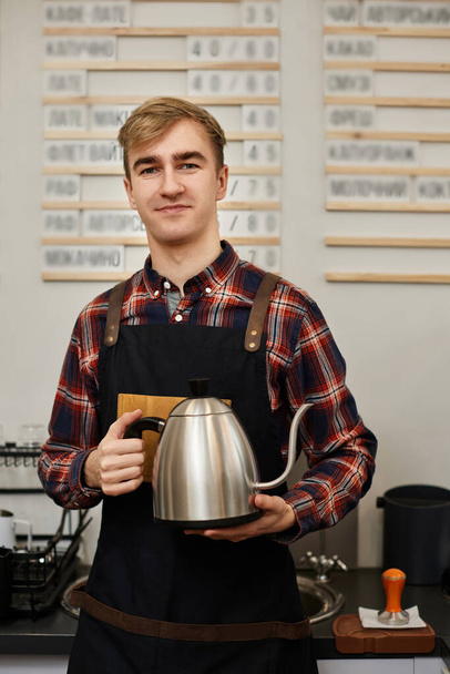 Professional barista man holding kettle at the coffee shop. - Fotó, kép