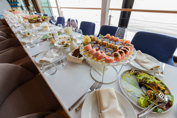 mesa servida con aperitivos fríos con un plato con rollos japoneses antes del banquete - Foto, Imagen