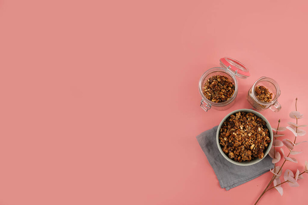A bowl with breakfast cereal granola on a pink surface arranged at the right side of the frame, a template - Foto, immagini