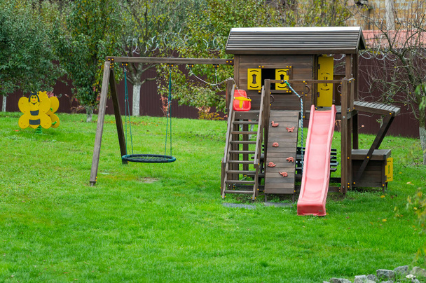 parco giochi in legno con elementi in plastica, altalene e scivoli per bambini in giardino - Foto, immagini
