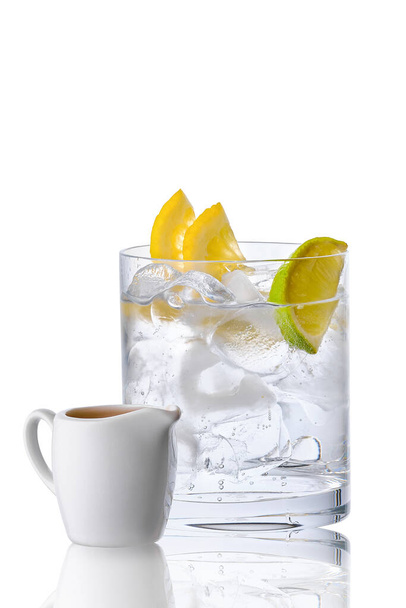 Glass with tonic and ice served with espresso in porcelain jug isolated on white background - Foto, Imagen