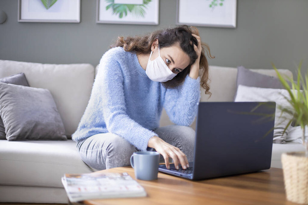 Jonge zakenvrouw die thuis werkt en een beschermend masker draagt na een coronavirus pandemie - Foto, afbeelding