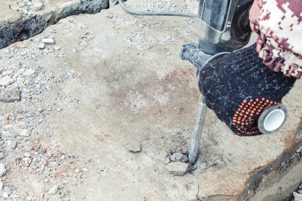 Homem trabalha com uma broca de martelo, quebrando tijolos ao ar livre. - Foto, Imagem