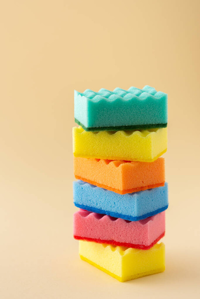 Stack of multicolored dishwashing sponges on neutral beige background, kitchen household and cleaning concept - Fotó, kép