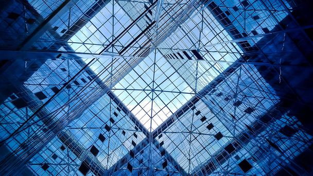 Toimistorakennuksen lasikupoli ja peilattu julkisivu, joka heijastaa taivasta ja rakennuksen rakenteen elementtejä, näkymä rakennuksen sisältä. - Valokuva, kuva