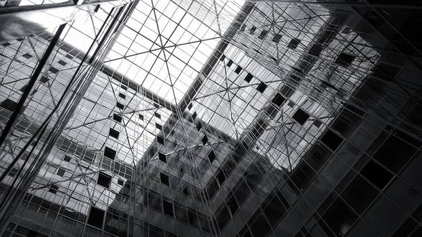 La cúpula de cristal del edificio de oficinas y la fachada espejada que refleja el cielo y los elementos de la estructura del edificio, Vista desde el interior del edificio. - Foto, imagen