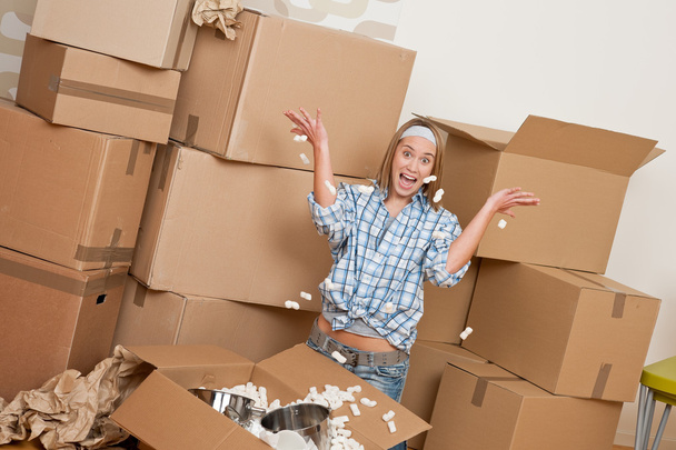 Moving house: Happy woman unpacking box in new home, kitchen, pots and pans - Zdjęcie, obraz