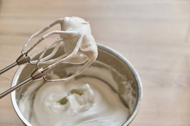 Whipped egg whites and other ingredients for cream or as a ingredient for peaking on wooden table, closeup - Fotografie, Obrázek