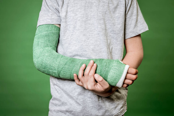 mid section of boy with broken arm with green plaster - Fotografie, Obrázek