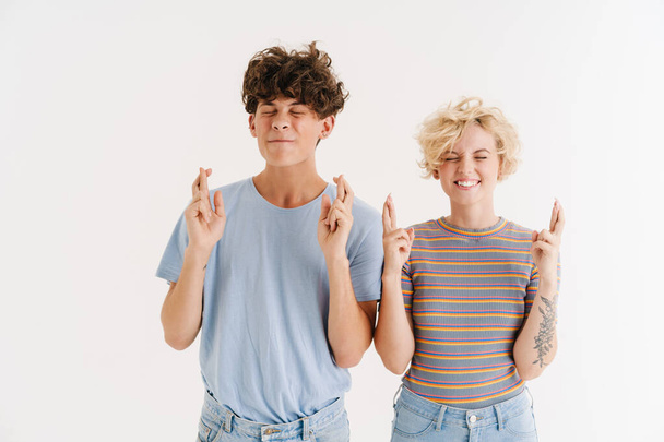 Image of happy young loving couple showing hopeful fingers crossed gesture isolated over white background - Foto, Imagem