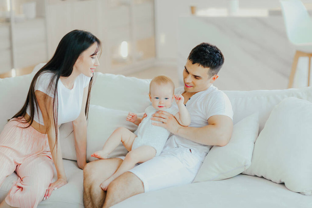 Father, mother and little son are relaxing on sofa in living room. Child care and parenting - Foto, Imagen