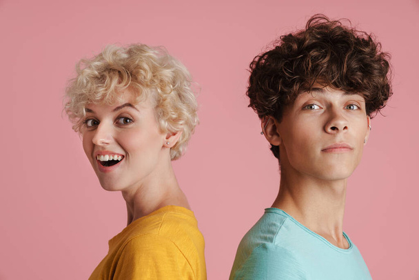 Attractive young couple of teenagers wearing t-shirts standing isolated over pink background, close up - Φωτογραφία, εικόνα