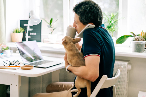 The young man with dog working from home - Photo, Image