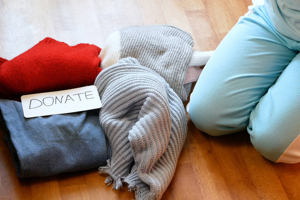 donna smistamento vestiti jeans, maglione, giacche per donazione a casa, concetto di seconda mano, primo piano  - Foto, immagini