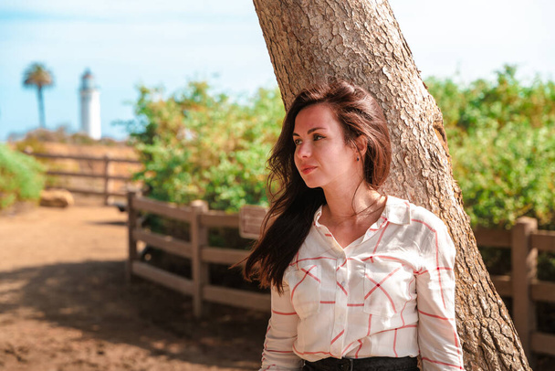 Приваблива жінка в білій сорочці йде вздовж берега з видом на маяк Пойнт Вісенте в Лос-Анджелесі. - Фото, зображення