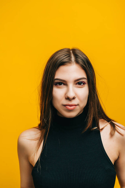 Portrait of attractive young woman with brunette hair looking on camera. isolated on yellow background with copy space, studio shot. - Foto, imagen