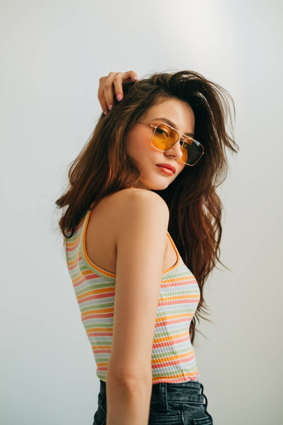 Portrait of attractive stylish woman in sunglasses with long brunette hair in studio. - Photo, image