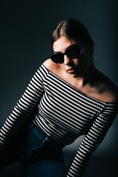 Portrait of attractive stylish woman in sunglasses with long brunette hair on black background in studio.	 - Zdjęcie, obraz