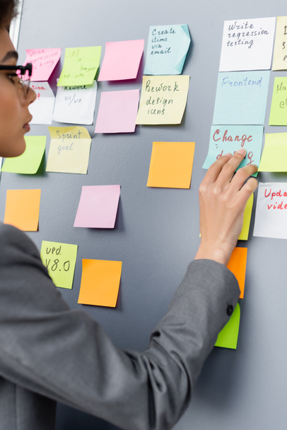 Blurred african american businesswoman looking at colorful sticky notes with lettering  - Photo, Image