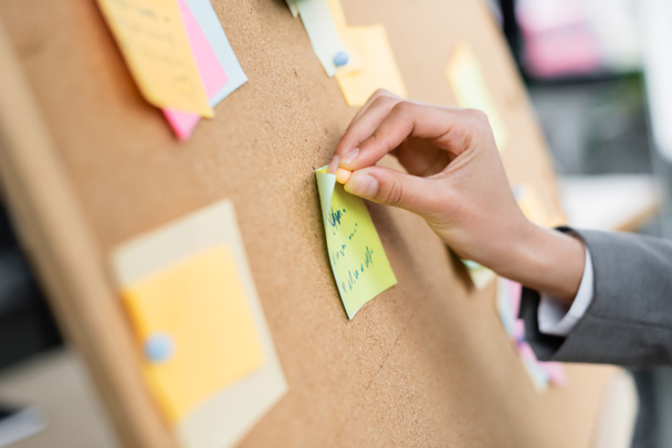Cropped view of businesswoman attaching sticky note on board  - Photo, Image