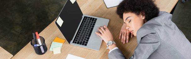 Afrykański amerykański bizneswoman leżące z zamkniętymi oczami w pobliżu laptopa na stole, baner  - Zdjęcie, obraz