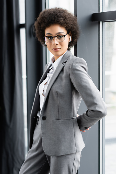 Afrykański amerykański bizneswoman w okularach i słuchawkach stojących w pobliżu okna  - Zdjęcie, obraz
