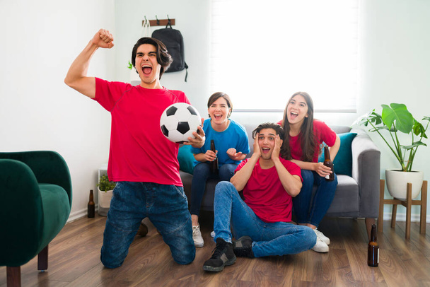 はい、スコア！サッカーの熱狂的なファンは、スポーツジャージを着て、自宅で自分の好きなチームの勝利を祝う  - 写真・画像