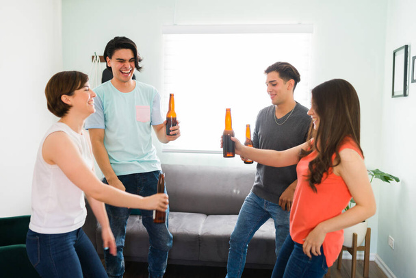 E 'ora di fare festa! Allegri amici del college che bevono birra e ridono mentre ballano una canzone allegra in soggiorno - Foto, immagini