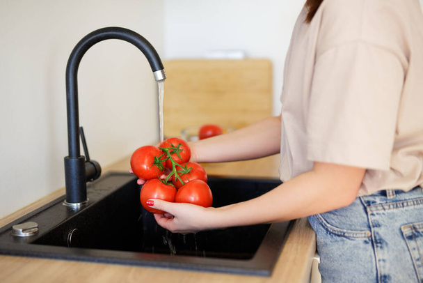 vrouw wassen tomaten onder water voor het koken - Foto, afbeelding
