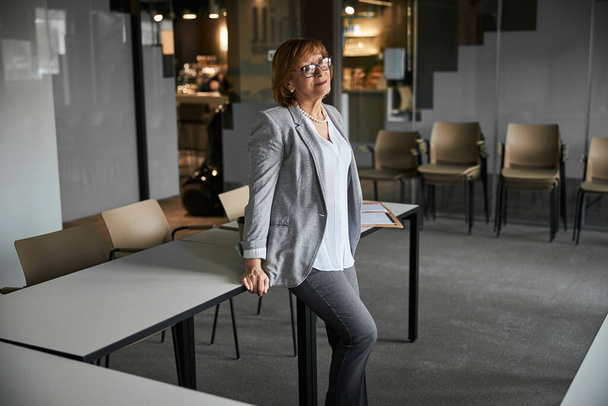 Business worker standing in office with her back to table - Valokuva, kuva
