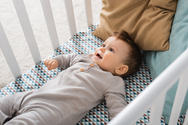 high angle view of infant boy lying in baby crib - Foto, afbeelding
