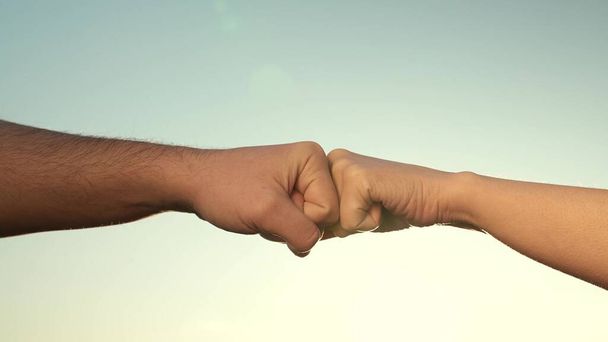 Male and female fists against the sky, trust, harmony, friendship. A fist to a fist is a sign, expresses consent, a gesture of respect. Teamwork concept. Lifestyle business team hands fists close up. - Foto, immagini