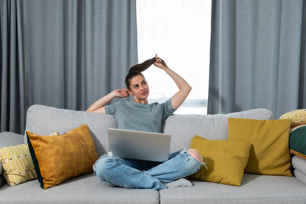 Young happy freelance entrepreneur woman sits satisfied in her apartment with laptop and smiling because she completed a very important business project task for a job she got online, business concept - Photo, image